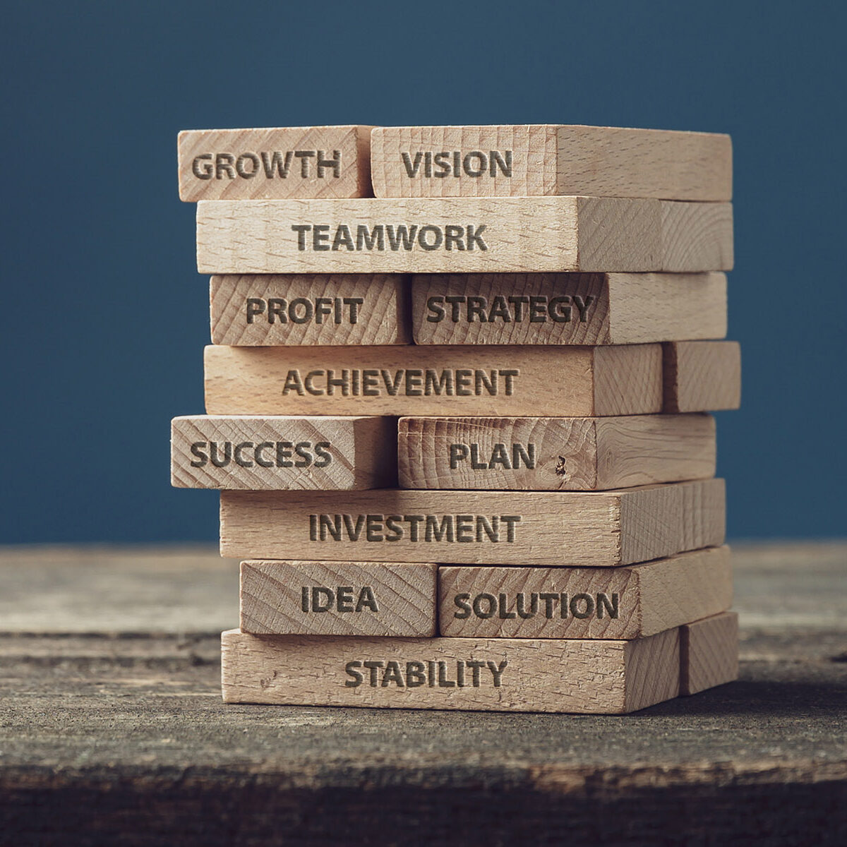 Stack of wooden pegs with words of personal and business development, from idea and vision to growth and success.