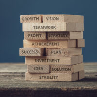 Stack of wooden pegs with words of personal and business development, from idea and vision to growth and success.