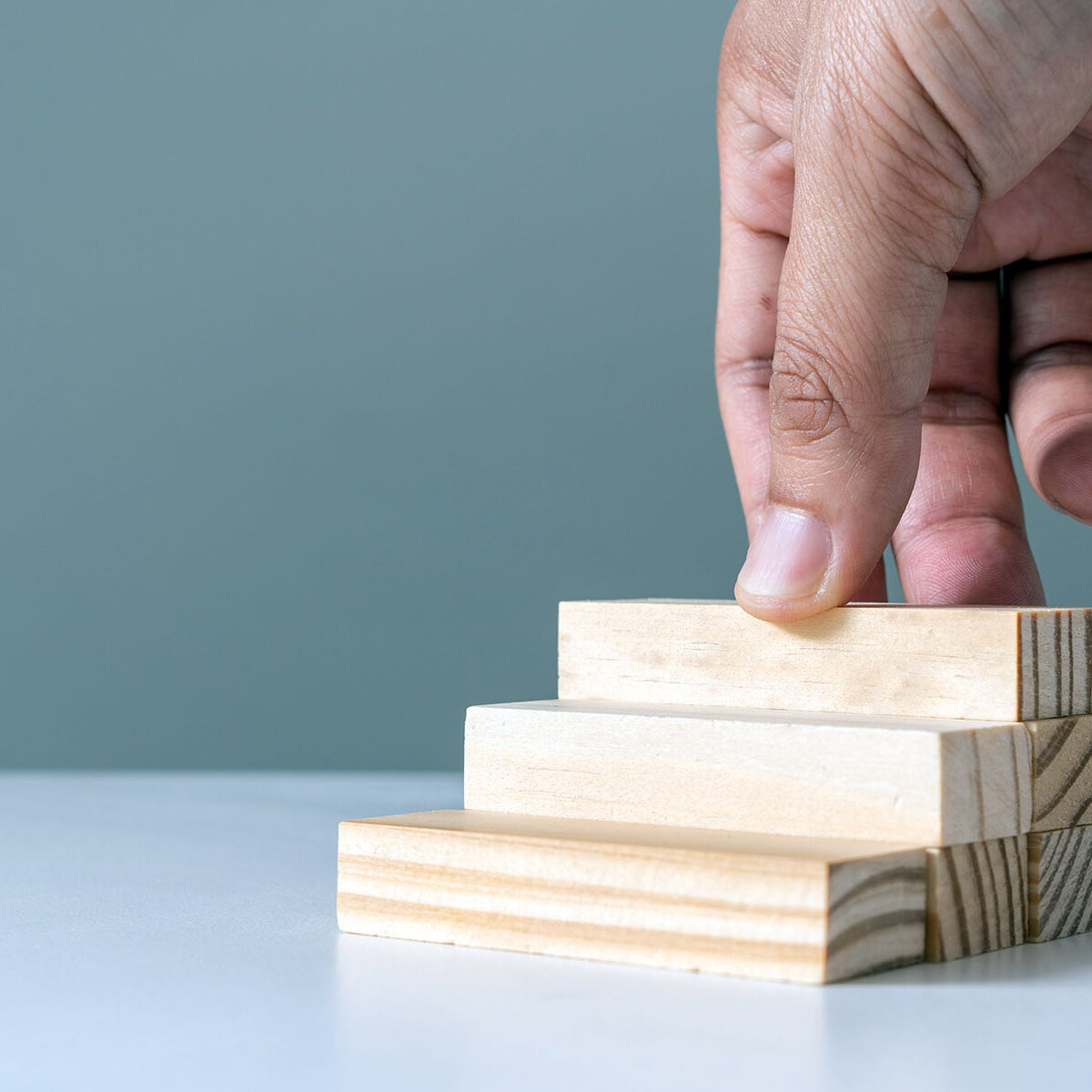 Hand arranging wood block stacking as step stair or ladder career path concept for business growth success process